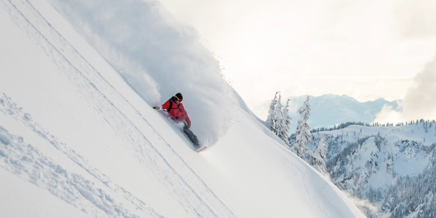 Man on snowboard riding down a steep slope wearing Superfeet Winter insoles.