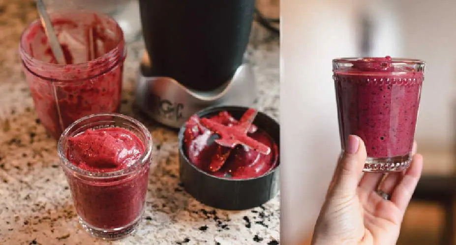 A hand holds a red smoothie in a glass cup